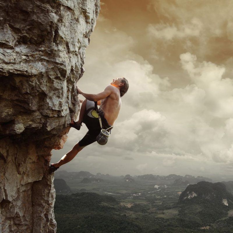 19362576 - young man climbing natural rocky wall with tropical valley on the background