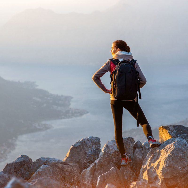 39049555 - young traveler with backpack standing on the big stones on the mountain and observing locality