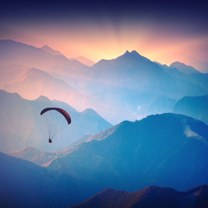 40622700 - silhouette of paraglide flying over the high mountains in a light of sunrise. ukrainian carpathian valley.