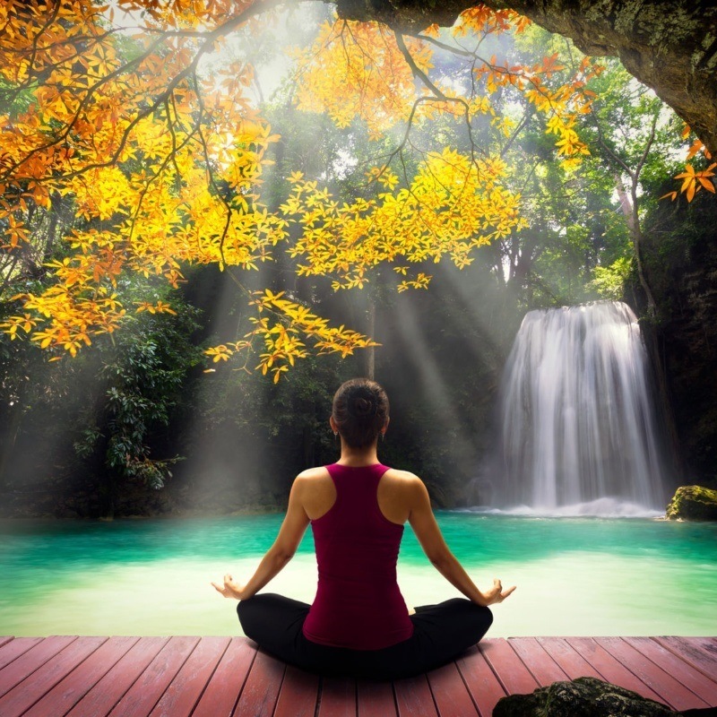 41619177 - young woman in yoga pose sitting near watefall rear view