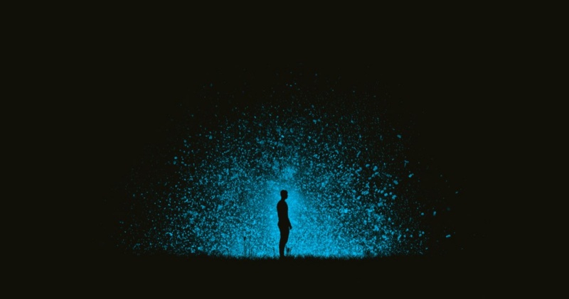 A man's silhouette glowing in the dark, surrounded by energy