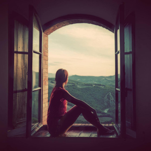 young woman looking out window contemplating