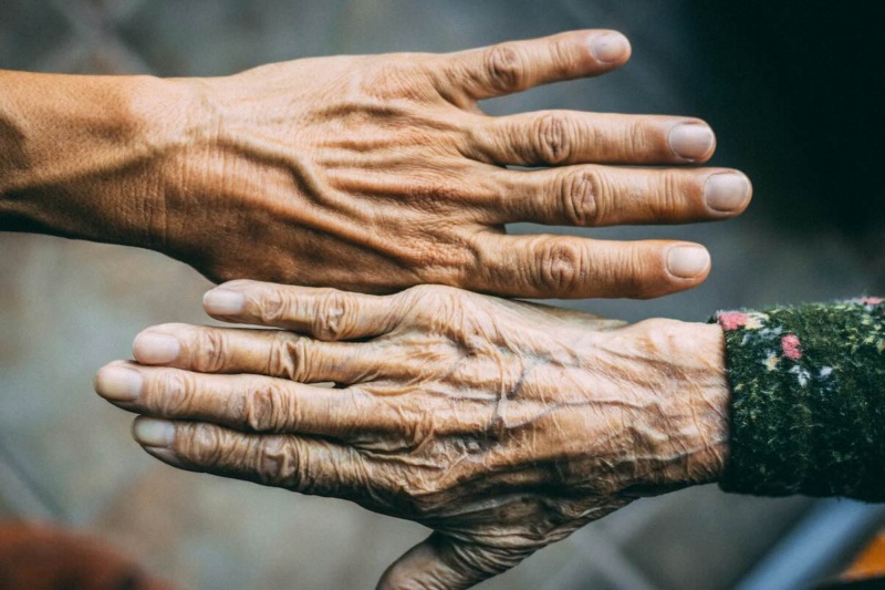 Law of constant change represented by two aging hands with wrinkles