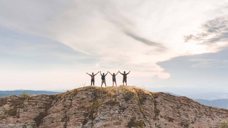 Group of people on mountain celebrating having overcome self-limiting beliefs 