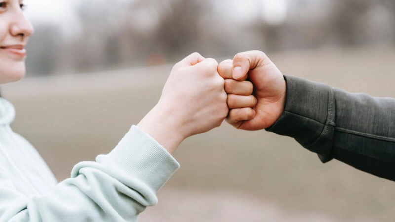 Confident woman bumping fists with a friend