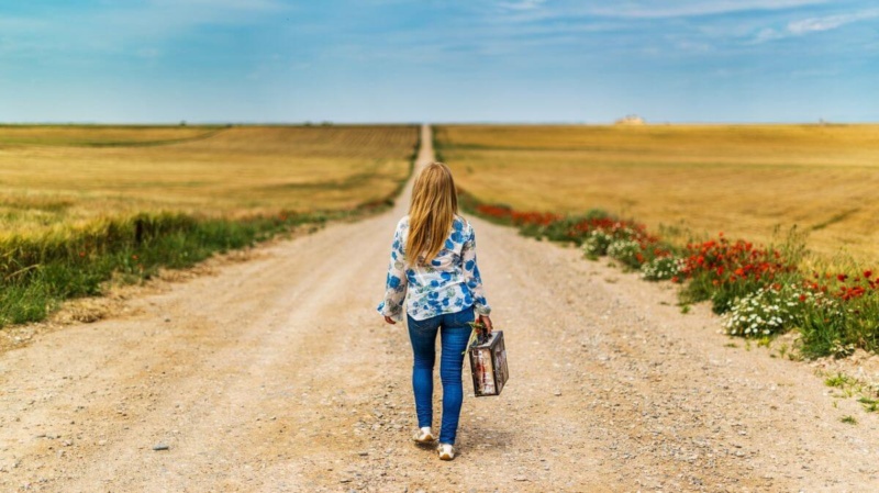 Girl walking down a dirt path with a briefcase