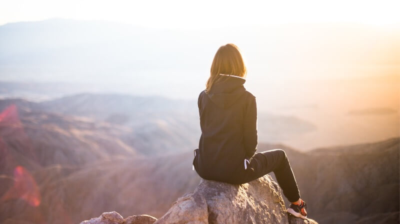 Woman sitting on mountain top practicing Mind Power