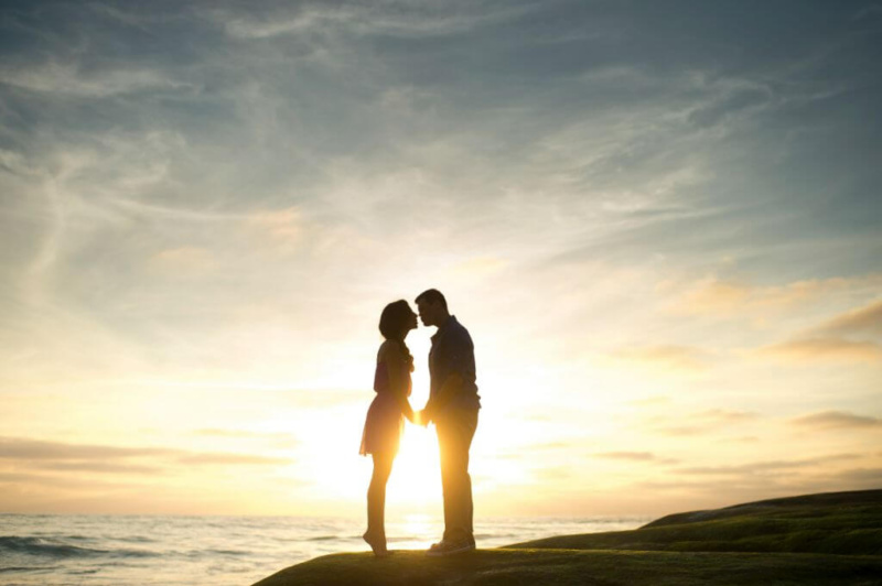 Soulmates at sunset kissing by the ocean