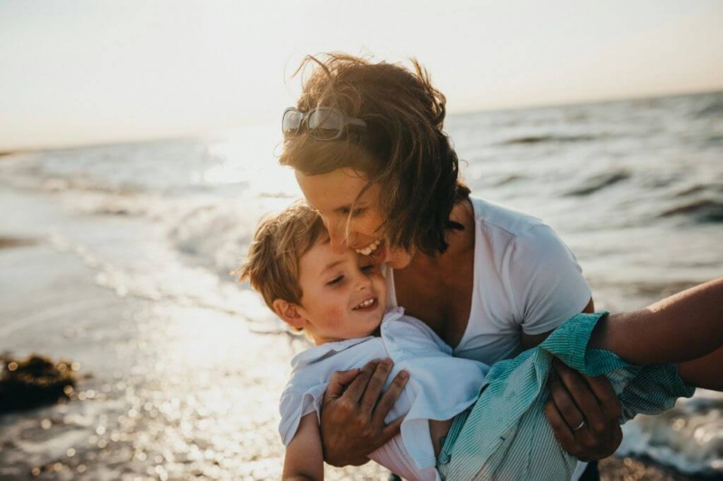 A high vibration woman playing with her son by the ocean